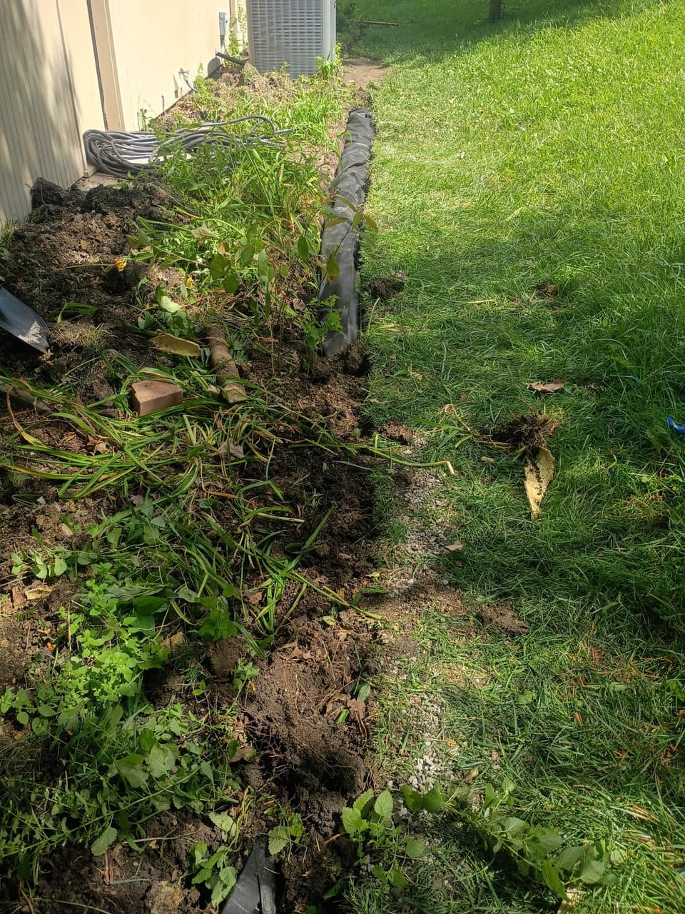 Open trench dug along a house foundation for a drain line