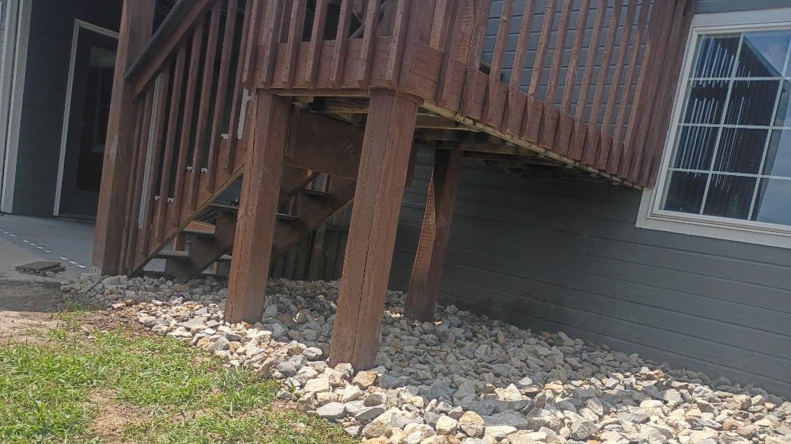 River rock drainage bed installed under the deck along the foundation