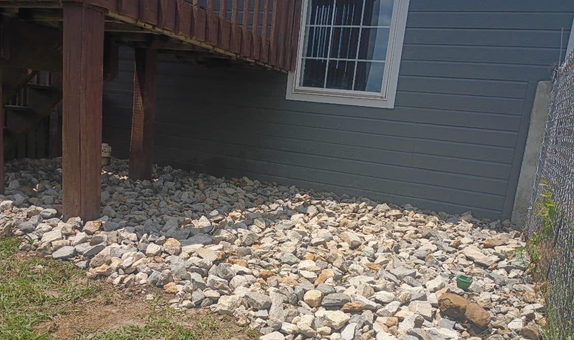 Finished rock drainage bed running along the base of the house wall