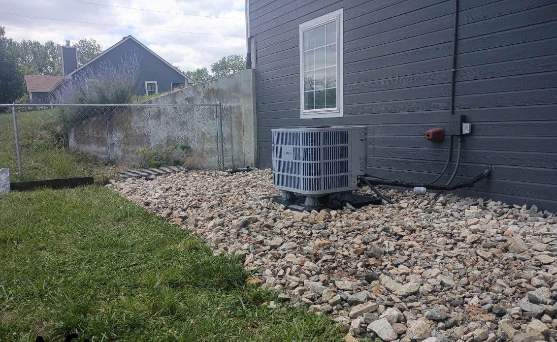Rock drainage bed carried around the air conditioning unit to the fence line