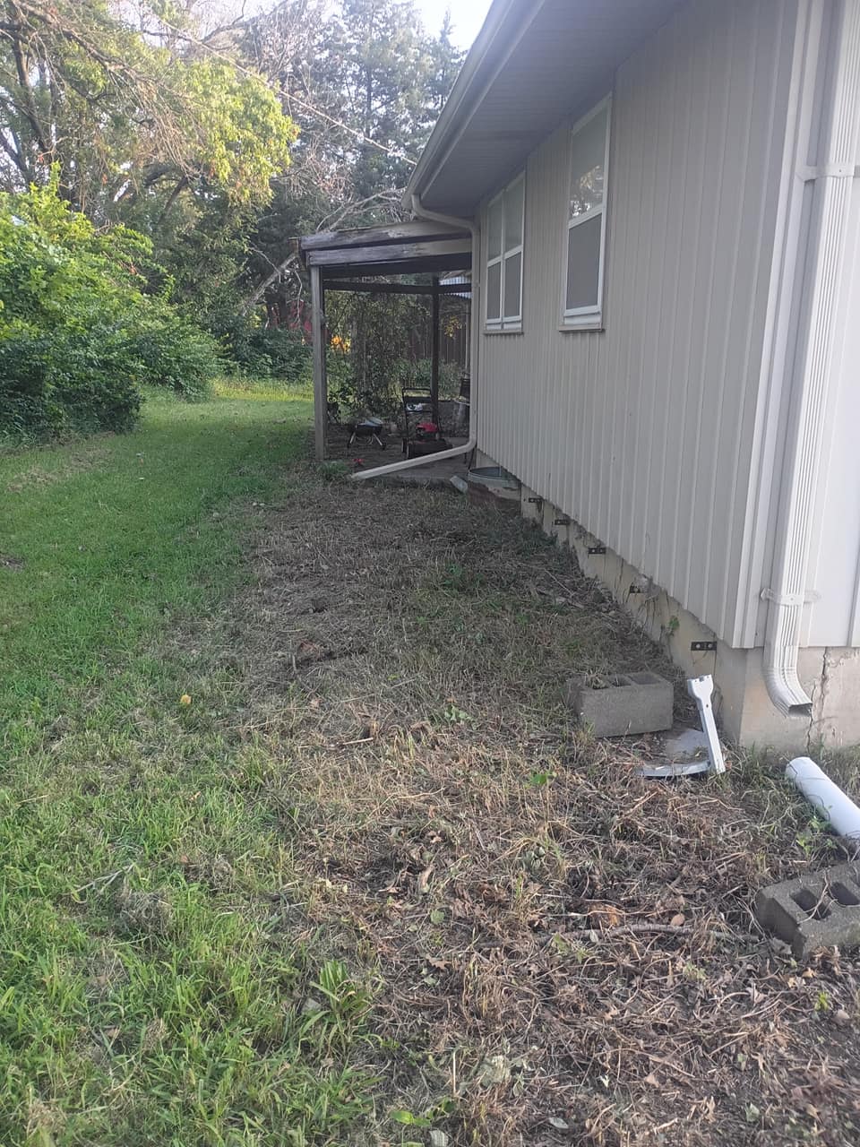 The same stretch cleared, with the siding and downspout visible again
